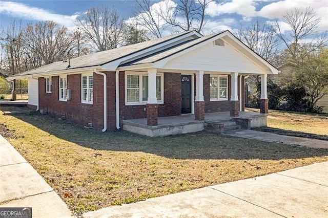 bungalow-style house with covered porch, brick siding, and a front yard