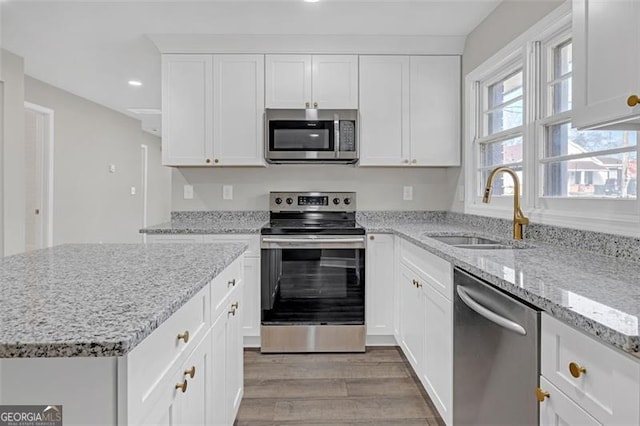 kitchen featuring recessed lighting, appliances with stainless steel finishes, white cabinets, a sink, and wood finished floors