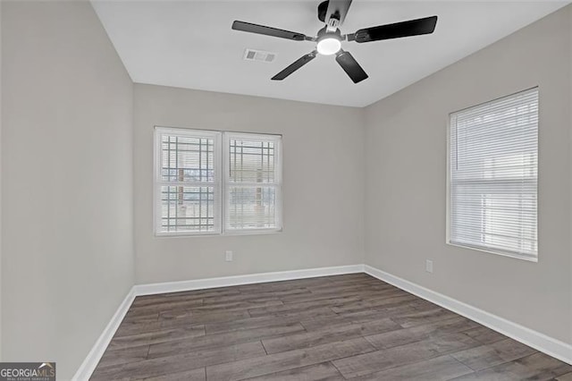 unfurnished room with dark wood-type flooring, visible vents, and baseboards