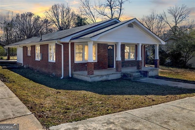 bungalow-style home with brick siding, crawl space, a porch, and a front yard