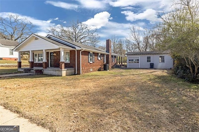 exterior space featuring covered porch, brick siding, an outdoor structure, a chimney, and a front yard