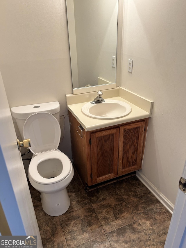 bathroom with toilet, vanity, and baseboards