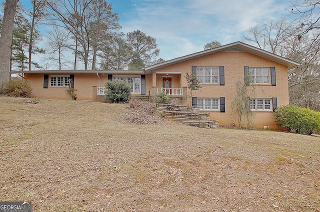 split level home featuring a front lawn and brick siding