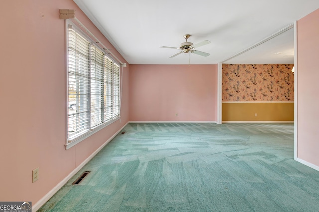 empty room with visible vents, a ceiling fan, light carpet, baseboards, and wallpapered walls