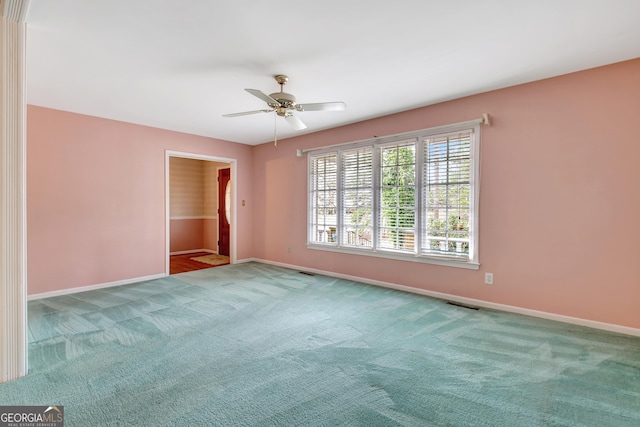 carpeted empty room featuring baseboards, visible vents, and ceiling fan