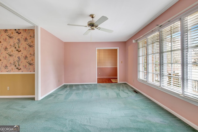 carpeted spare room featuring ceiling fan, baseboards, and wallpapered walls