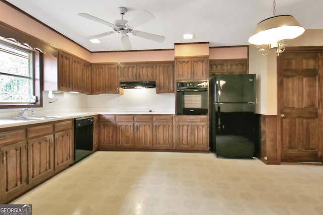 kitchen featuring brown cabinets, hanging light fixtures, under cabinet range hood, light countertops, and black appliances