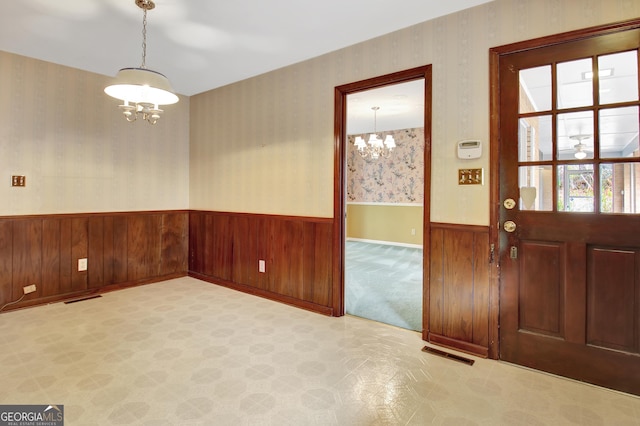 entrance foyer with a notable chandelier, visible vents, light carpet, wainscoting, and wallpapered walls