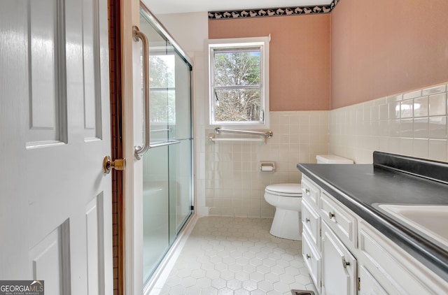 bathroom with a shower stall, vanity, tile walls, and tile patterned floors