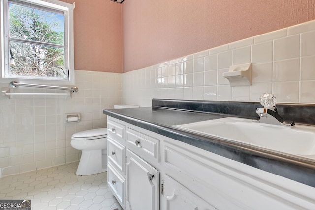 bathroom featuring a wainscoted wall, tile walls, toilet, vanity, and tile patterned floors