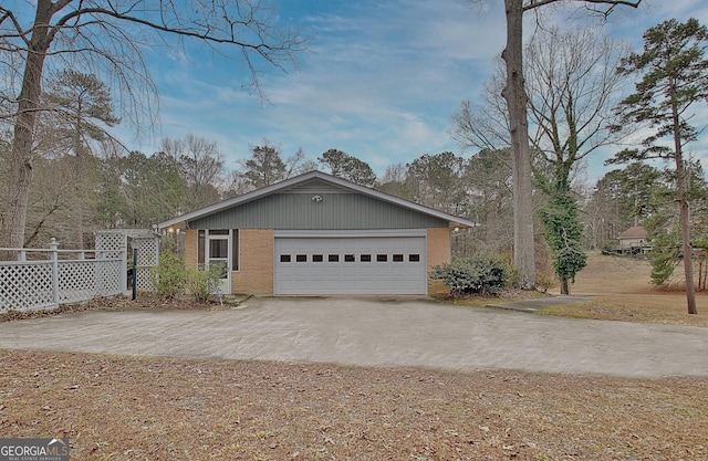 view of property exterior with brick siding, driveway, an attached garage, and fence