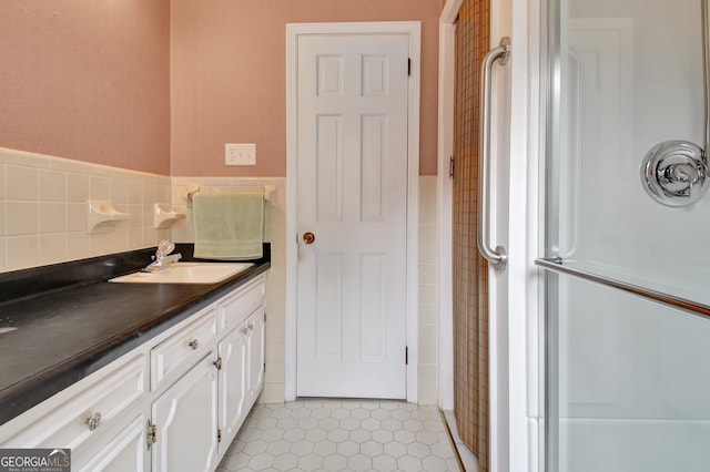 full bath with wainscoting, tile patterned flooring, tile walls, and vanity