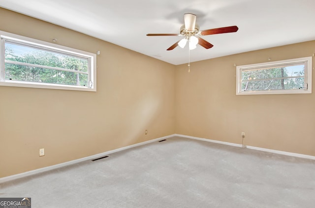 spare room with light carpet, plenty of natural light, visible vents, and baseboards