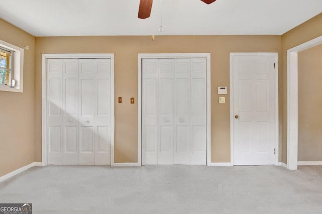 unfurnished bedroom featuring baseboards, ceiling fan, light colored carpet, and multiple closets