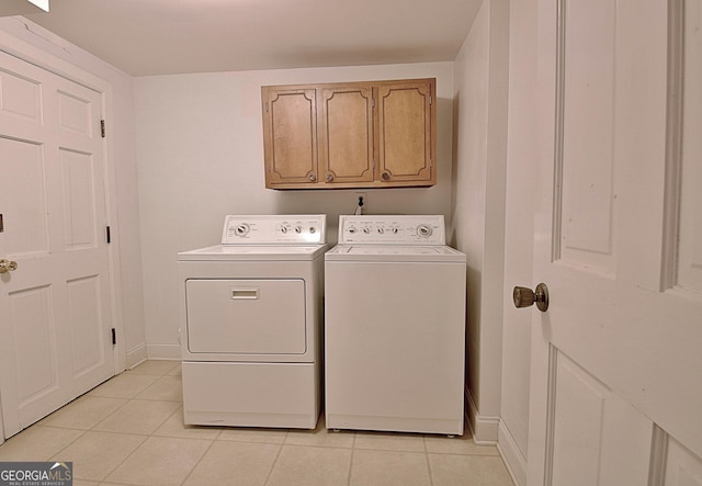 laundry room with light tile patterned flooring, washing machine and dryer, cabinet space, and baseboards