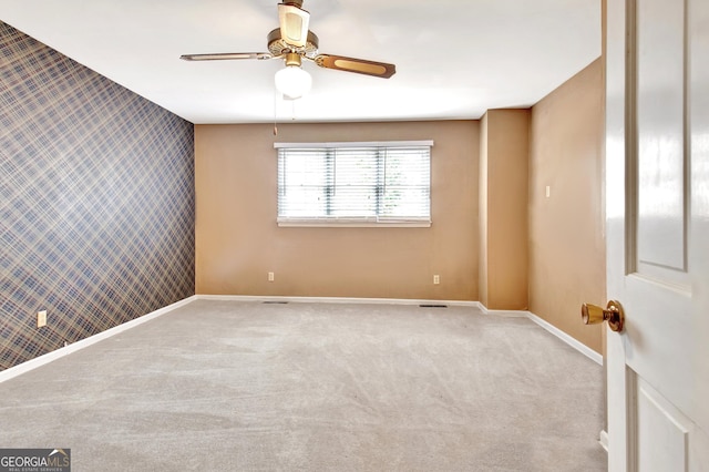 spare room featuring an accent wall, light colored carpet, baseboards, and wallpapered walls