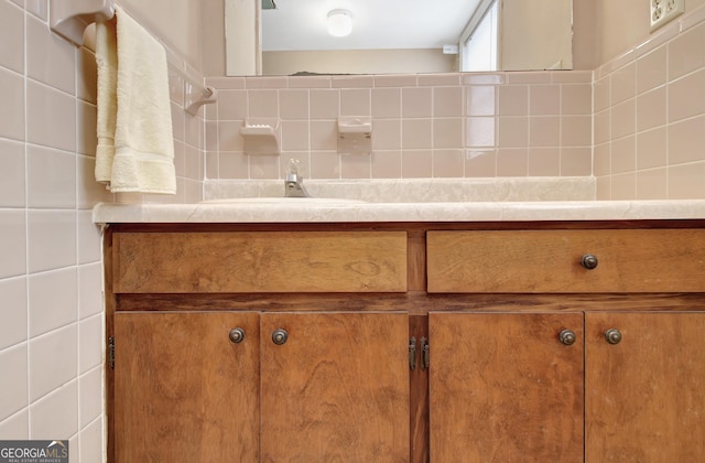 bathroom with a sink, tile walls, and decorative backsplash