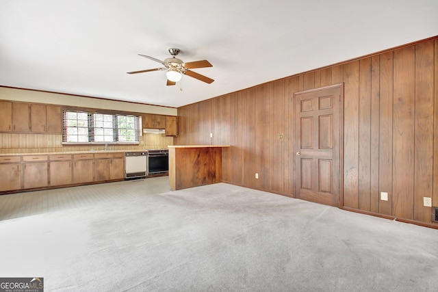 unfurnished living room with a ceiling fan, light colored carpet, and wood walls