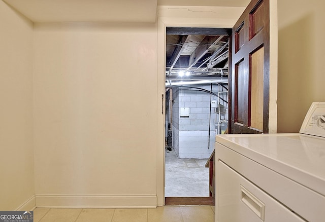 laundry room featuring concrete block wall, washer / dryer, and baseboards