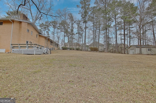 view of yard featuring a detached garage and a wooden deck