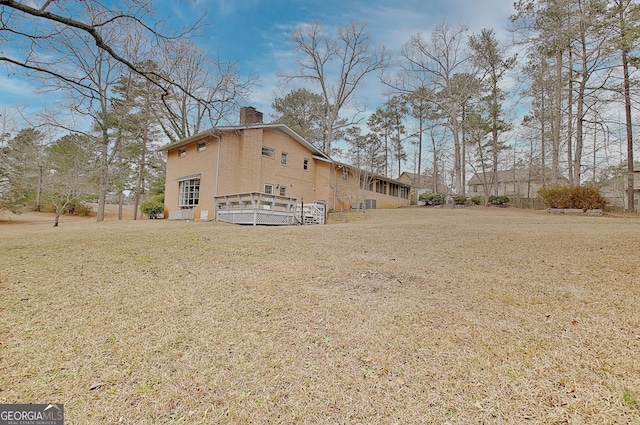 exterior space featuring a yard, a chimney, and a wooden deck