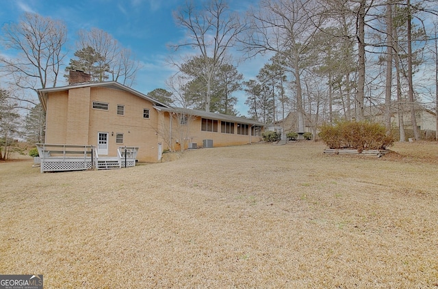 back of house with a chimney, a wooden deck, a lawn, and central air condition unit