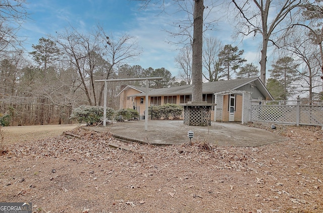 view of front of house featuring a patio area, fence, and brick siding