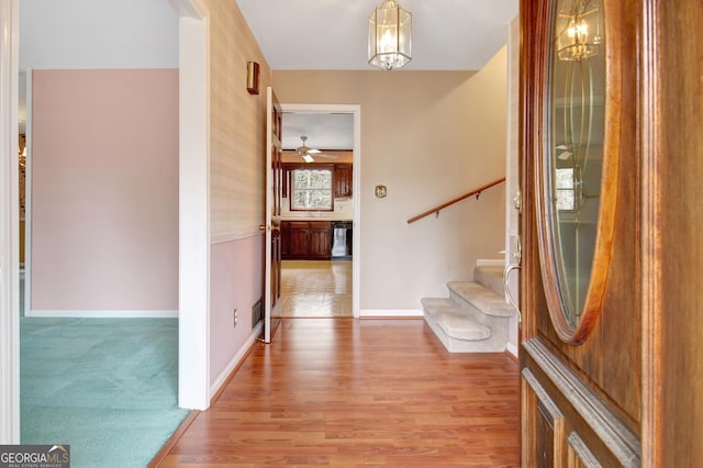 entrance foyer featuring a chandelier, stairway, light wood-type flooring, and baseboards