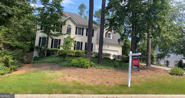 colonial home featuring an attached garage and stucco siding