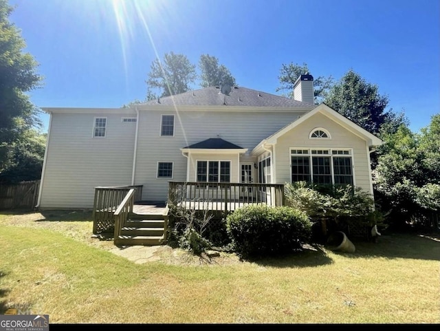 back of house with a chimney, a lawn, and a wooden deck