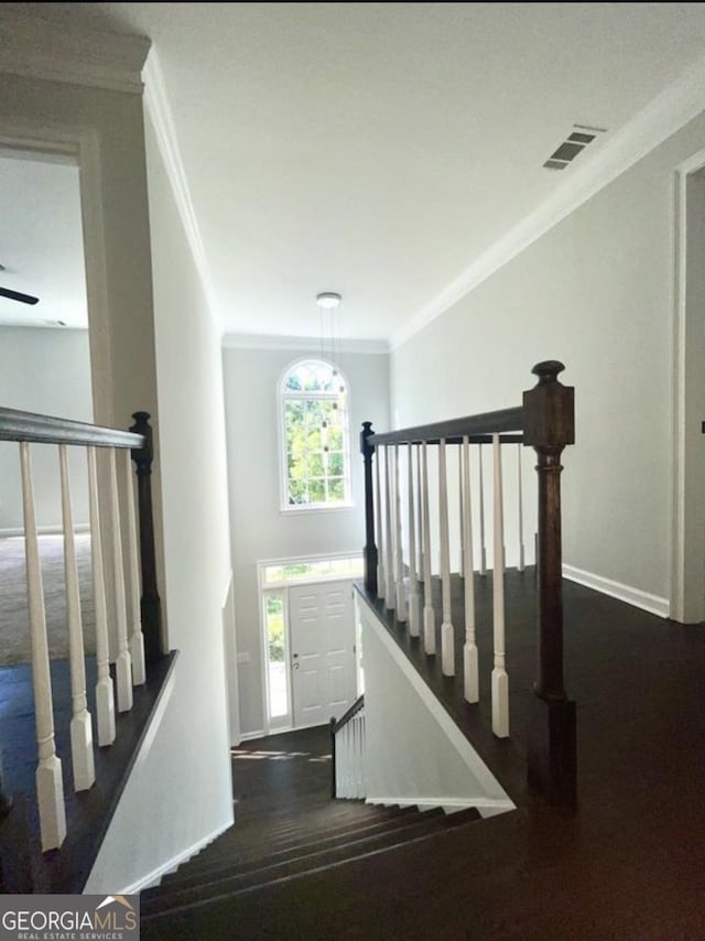 staircase featuring baseboards, visible vents, ornamental molding, and wood finished floors