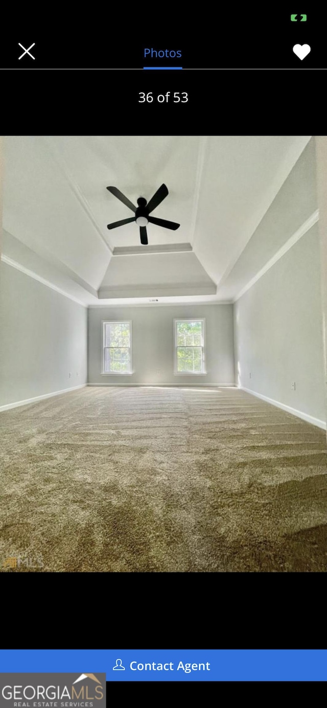 carpeted empty room featuring a tray ceiling, ceiling fan, and baseboards