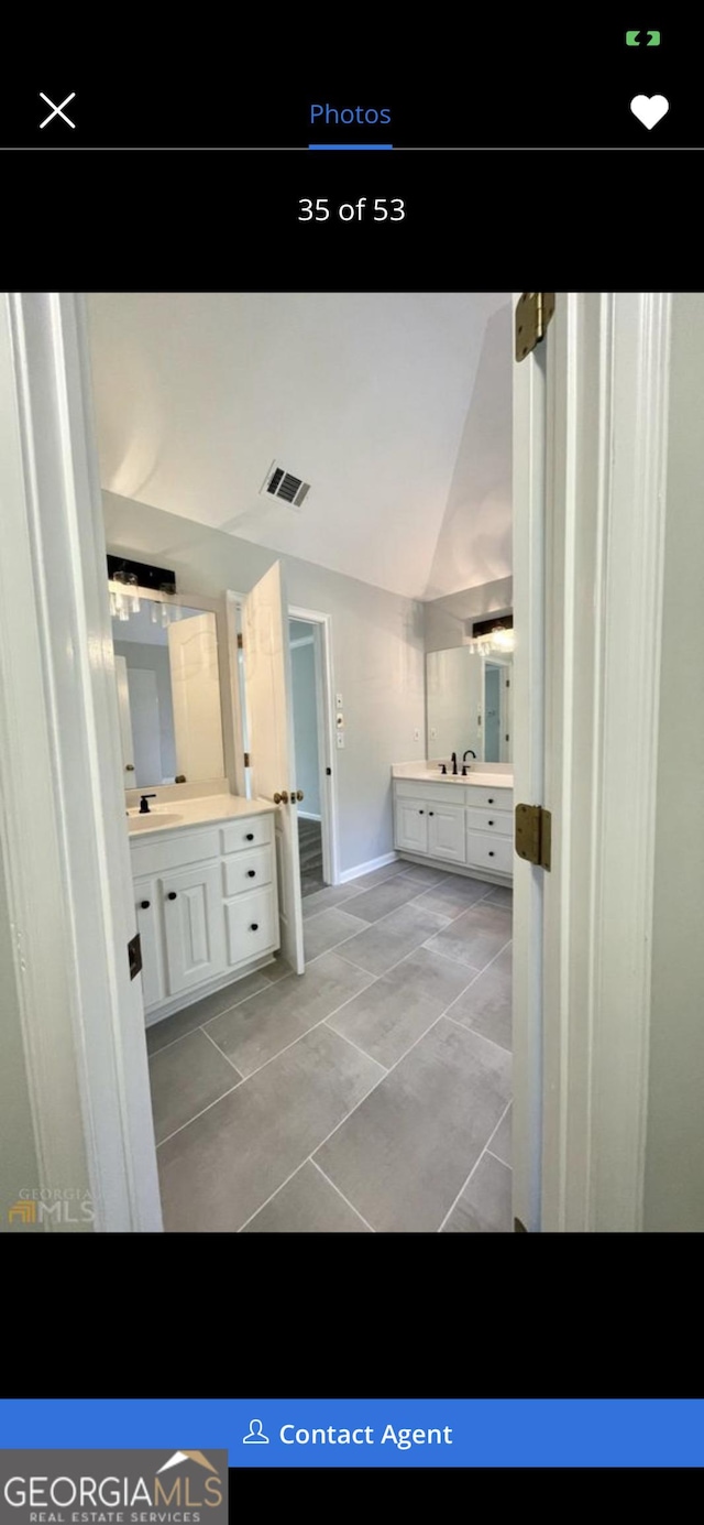 full bath featuring visible vents, vaulted ceiling, vanity, and tile patterned floors