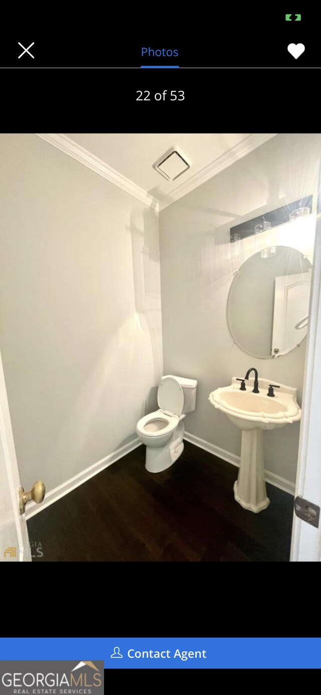 half bath with baseboards, wood finished floors, toilet, and crown molding