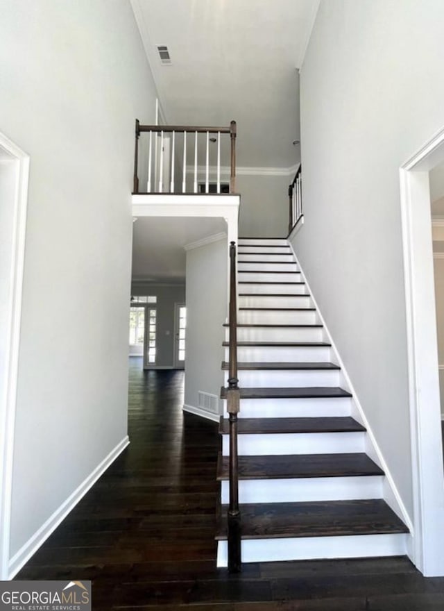 stairway with visible vents, crown molding, baseboards, and wood finished floors