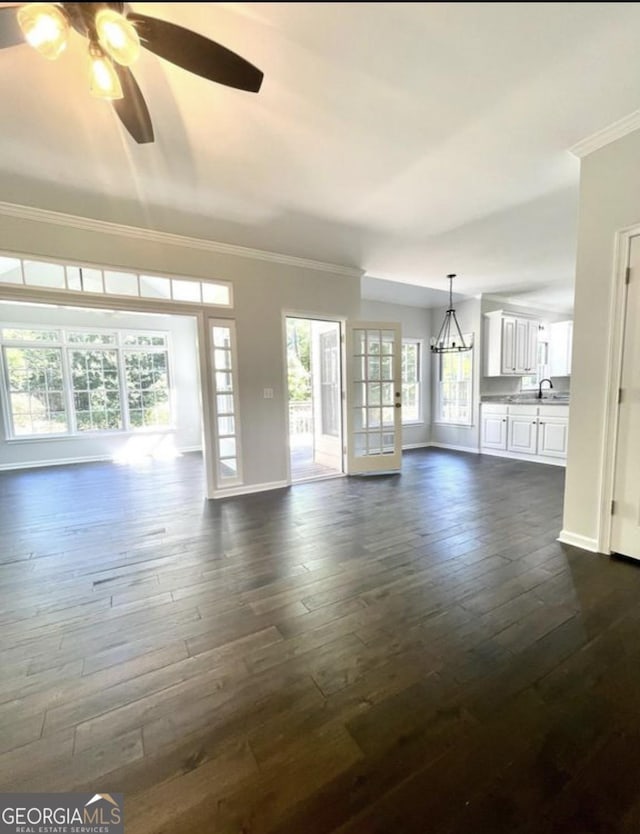 unfurnished living room featuring dark wood-style floors, ornamental molding, a sink, ceiling fan, and baseboards