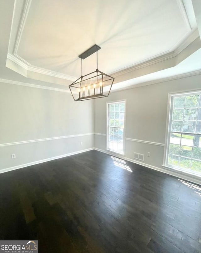 empty room with baseboards, visible vents, a raised ceiling, dark wood-style flooring, and crown molding