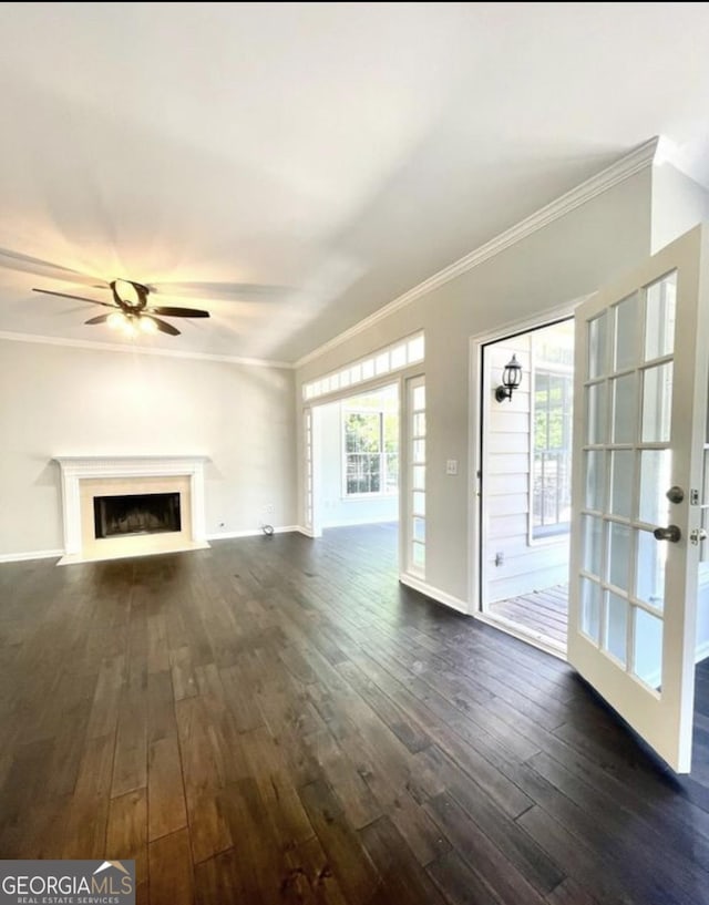 unfurnished living room with dark wood-style floors, crown molding, a fireplace with flush hearth, ceiling fan, and baseboards