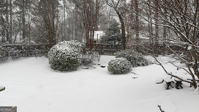 snowy yard featuring fence