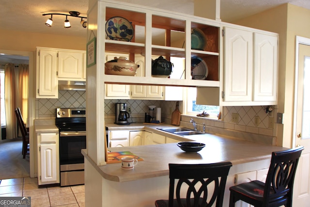 kitchen featuring electric range, a breakfast bar, a peninsula, under cabinet range hood, and a sink