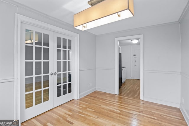 unfurnished room with light wood-type flooring, baseboards, crown molding, and french doors