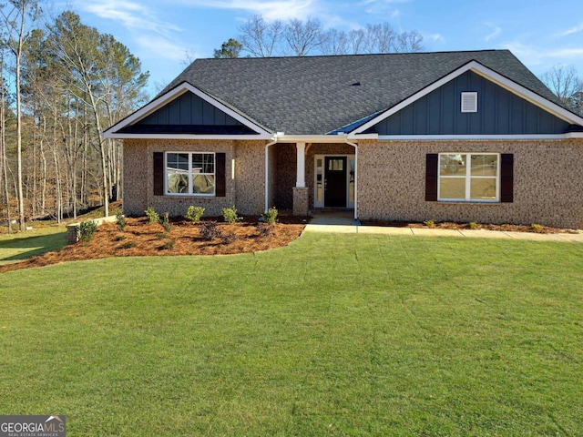 view of front of house with a shingled roof, brick siding, board and batten siding, and a front lawn