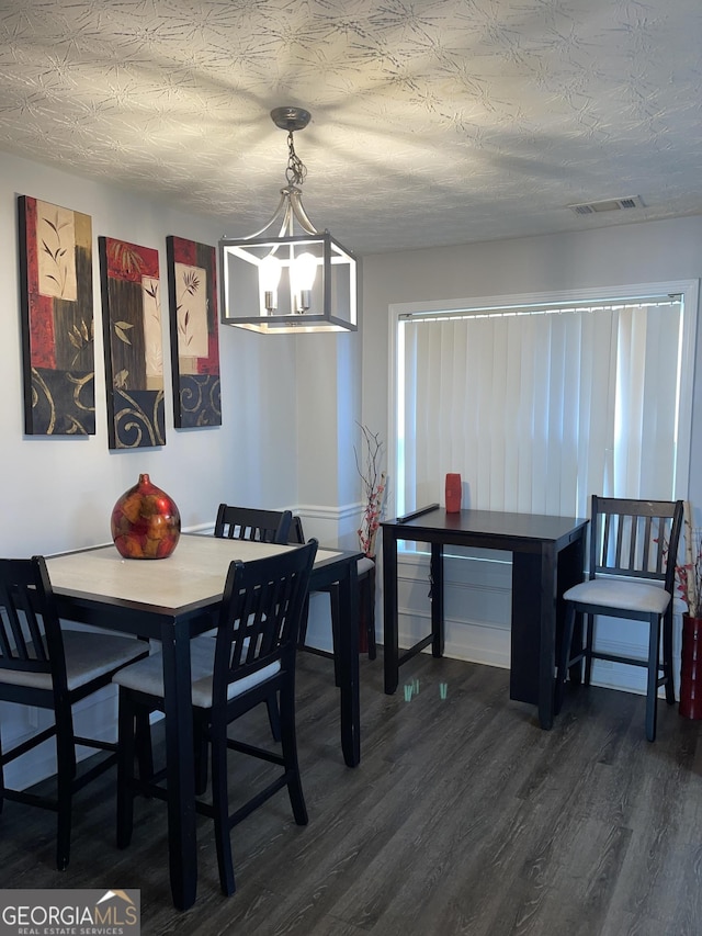 dining room with dark wood-style floors, visible vents, and a textured ceiling