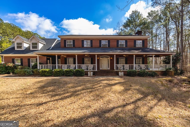 view of front of property with brick siding, a porch, and a front yard