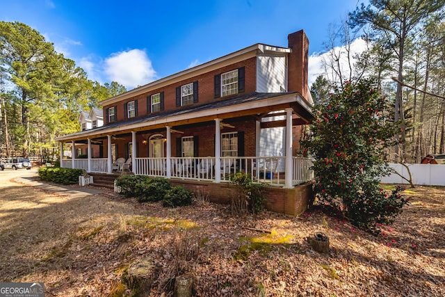 view of front of house with a chimney, fence, a porch, and brick siding