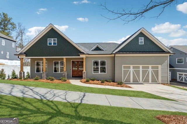 craftsman-style home with a garage, concrete driveway, a standing seam roof, french doors, and a front yard