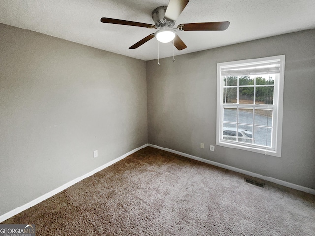 empty room featuring carpet floors, visible vents, baseboards, and a ceiling fan