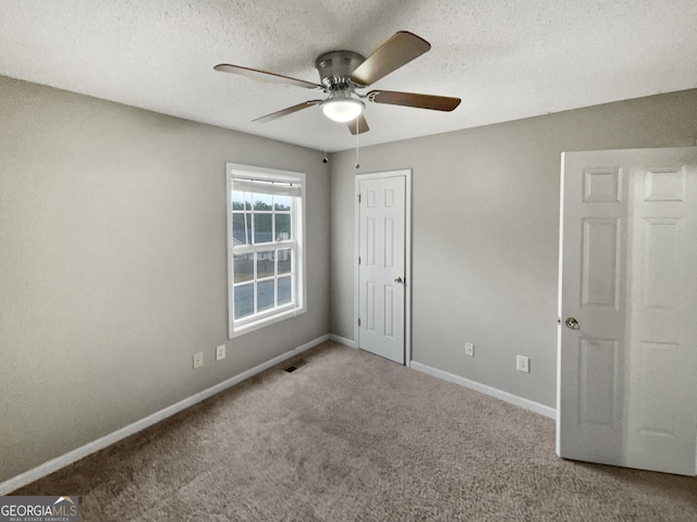 unfurnished bedroom with carpet, visible vents, ceiling fan, a textured ceiling, and baseboards