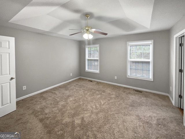 unfurnished bedroom with visible vents, baseboards, a raised ceiling, ceiling fan, and carpet flooring