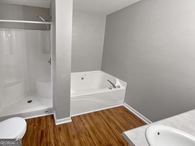 full bathroom featuring a stall shower, vanity, wood finished floors, baseboards, and a bath